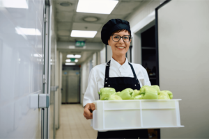Hospital Chef - Dublin 24 3 a woman wearing a chef hat and apron holding a container of green peppers. Chef, Hospital Chef, carrying food, 3Q Recruitment